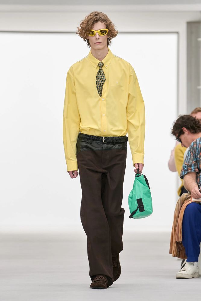 Oversized butter-yellow oxford shirt with a patterned tie and wide brown trousers, Loewe S/S 27, Paris.