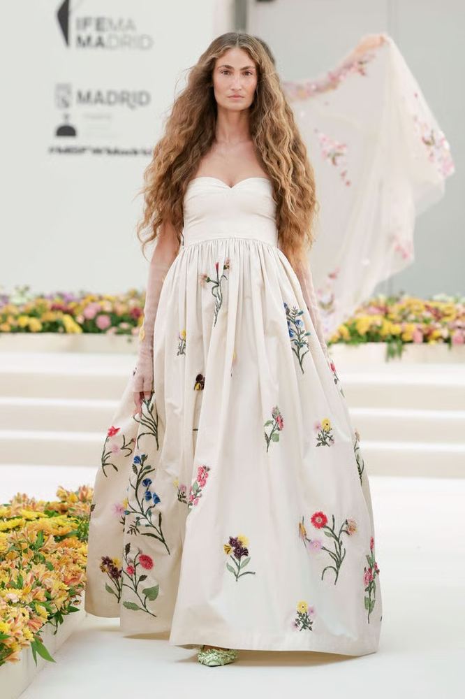 Ivory strapless gown with a full skirt embroidered in scattered wildflowers, Agua Bendita S/S 27, Madrid.