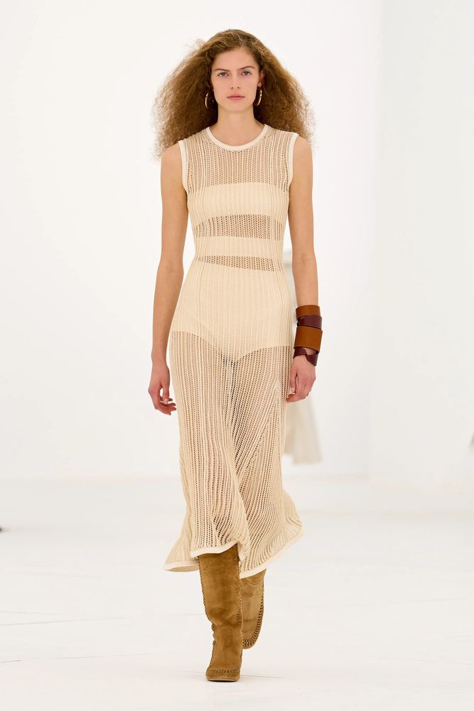 Ivory openwork knit dress layered over a sheer slip, with suede boots, Hermès S/S 27, Paris.